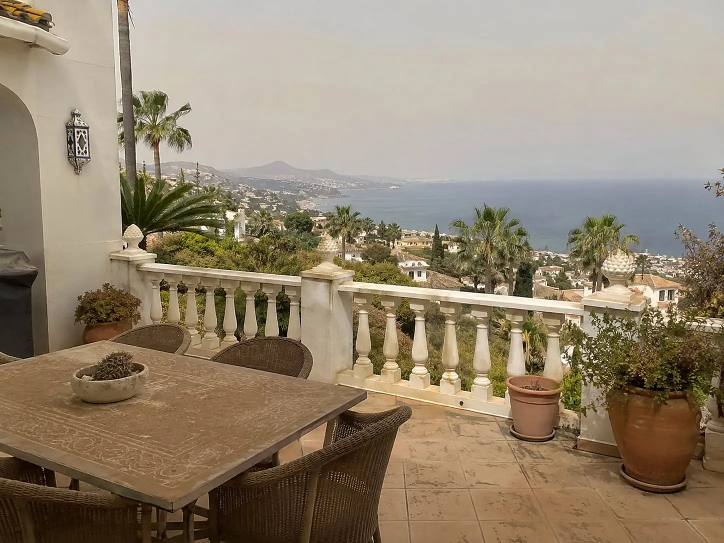 Terrace in Marbella with table, chairs and balustrade under a layer of calima dust, before cleaning